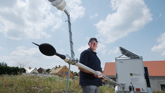 Jörg Puchmüller, Fluglärmschutzbeauftragter des Landes Sachsen, hält den Mast einer mobilen Messstation für Fluglärm.
