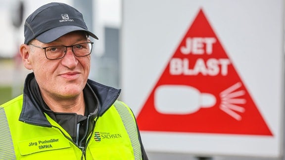 Jörg Puchmüller, Fluglärmschutzbeauftragter des Landes Sachsen, steht vor einem Warnschild vor Flugzeugturbinen am Flughafen Leipzig/Halle. 