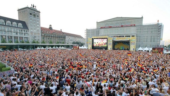 Fußballfans verfolgen auf dem Leipziger Augustusplatz ein Fußballspiel