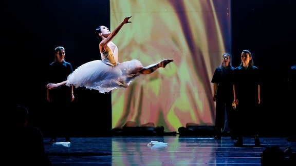 Eine springende Ballettänzerin scheint auf der Bühne zu schweben