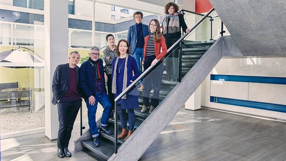 Die sieben Jury-Mitglieder des Deutschen Buchpreises steht aufgereit auf einer Treppe.