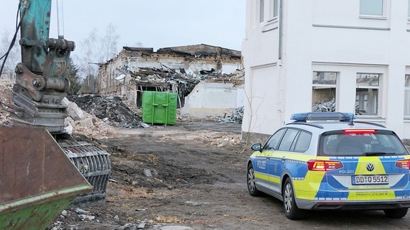 Ein Polizeiauto steht vor einem halb abgerissenen Gebäude und Schutthaufen in Naunhof.