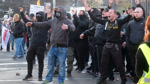 Teilnehmer der Demonstration der Initiative „Querdenken“ rufen und gestikulieren mit ausgebreiteten Armen auf dem Augustusplatz