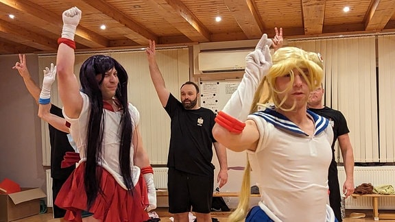 Männer in Faschingskostümen proben für Fasching einen Tanz. 