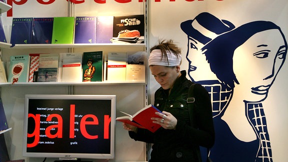 Auf der Buchmesse in Leipzig steht eine Besucherin am Stand des Verlags "poetenladen"