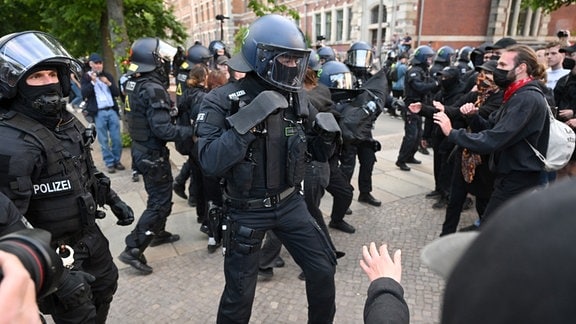 Bei Protesten gegen das Urteil im Prozess gegen Lina E. in Leipzig steht ein Polizist in Kampfposition vor Demonstranten. 