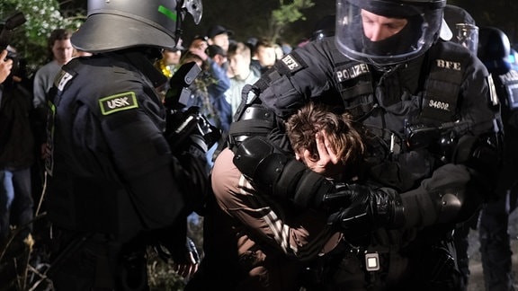 Ein Demonstrant wird von zwei Polizisten in Gewahrsam genommen.