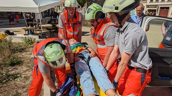 Eine Frau wird bei einer Rettungsübung auf einer Krankenliege von Rettungskräften behandelt. 