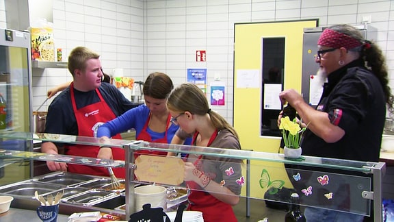 Sternekoch Stefan Marquard und mehrere Schüler kochen zusammen in einer Schulküche. 