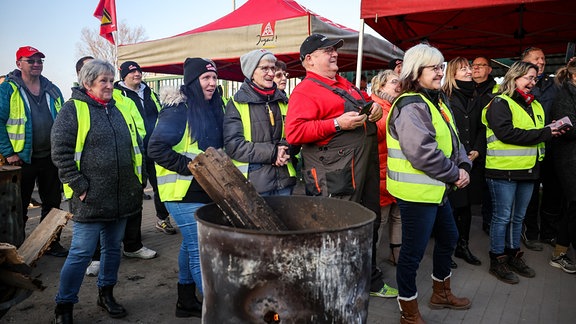 Streikende Mitarbeiter stehen beim Besuch von Sachsens Ministerpräsident Kretschmer vor dem Recycling-Betrieb SRW.