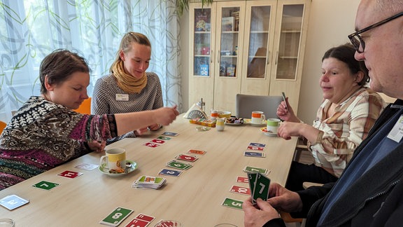 Drei Frauen und ein Mann spielen Karten.