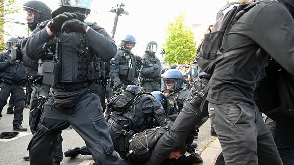 Bei Protesten gegen das Urteil im Prozess gegen Lina E. in Leipzig rangeln Polizisten und ein Demonstrant auf dem Boden.