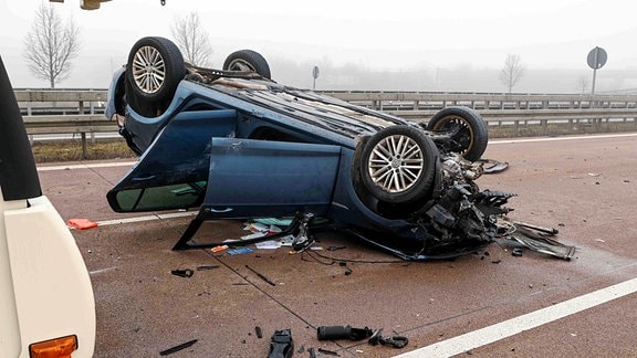 Ein Auto liegt auf dem Dach nach einem Unfall auf der Autobahn.