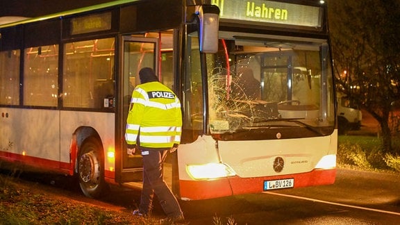 Ein Bus steht mit beschädigter Frontscheibe am Straßenrand.