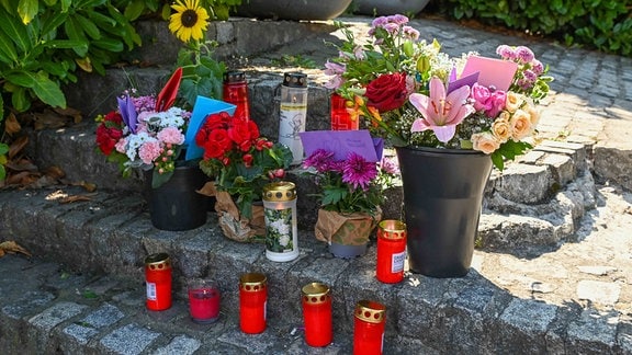 Blumen und Kerzen stehen an einem Erinnerungsort.