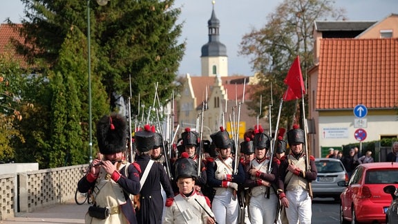 Darsteller von Soldaten aus der Zeit um 1813 marschieren zu einer Gefechtsdarstellung
