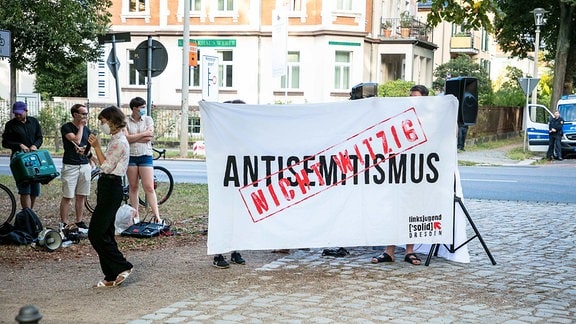 Proteste während des Auftritts der österreichischen Kabarettistin Lisa Eckhart, Menschen stehen um ein Transparent mit der Aufschrift "Antisemitismus - nicht witzig"