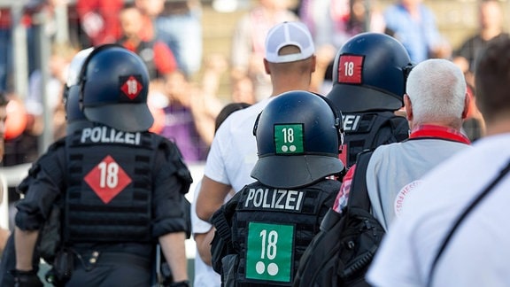 Polizisten in Kampfmontur zwischen Fußballfans