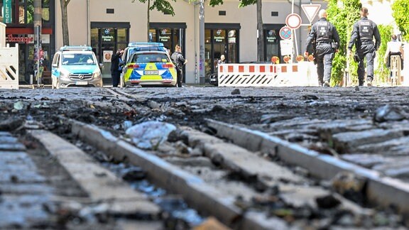 Polizeifahrzeuge stehen im Stadtteil Connewitz in Leipzig in einer Straße mit Brandresten der Ausschreitungen am Vorabend.