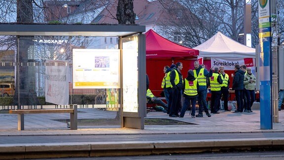 Mitarbeiter der Leipziger Verkehrsbetriebe haben sich an der Straßenbahnhaltestelle Angerbrücke zum Warnstreik versammelt.