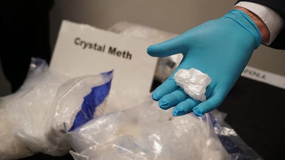 In Beuteln und auf einer Hand ist Crystal Meth zu sehen