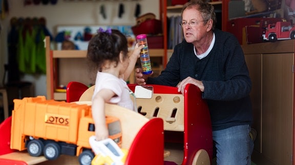 Tagesvater Franz Paschmann (75) in seiner Großtagespflege Flohnest in Düsseldorf spielt mit einem Kind.