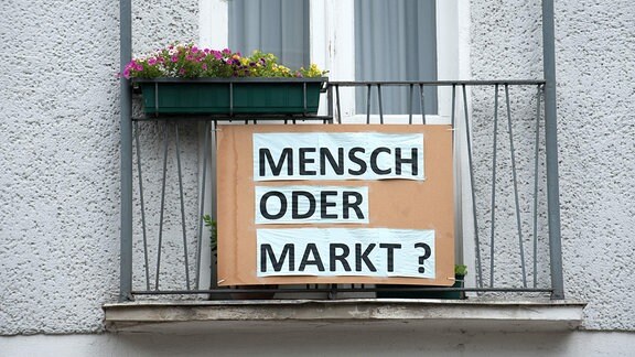 Mensch oder Markt? steht an einem Balkon
