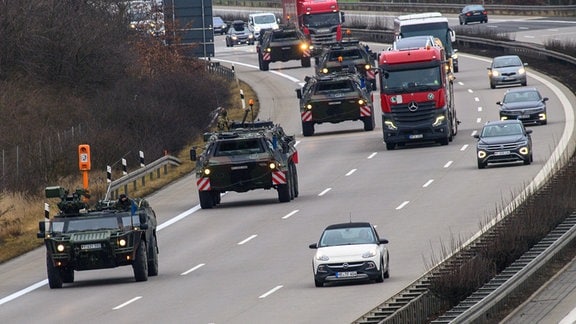 Fahrzeuge der Bundeswehr rollen im dichten Verkehr über die Autobahn A2.