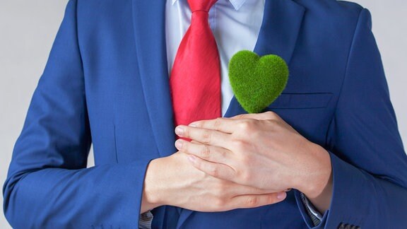 Geschäftsmann im Anzug, der ein grünes Herz hält
