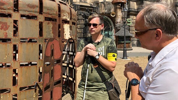 Besucher stehen neben einem der Getreidesilo des Werkes OPUŠTENÁ OBYDLI von dem Künstler Čestmír Suška.