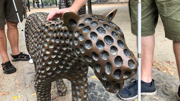 Nahaufnahme einer der Raubkatzenfiguren. Daniel Martins Hand tastet darüber.