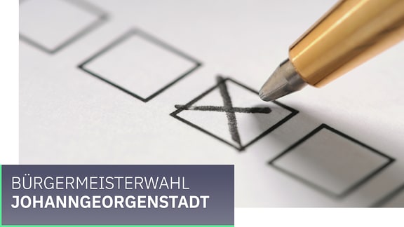 Wahl Gemeinde Johanngeorgenstadt. Ein Kreuz wird mit einem Stift auf einem Zettel gesetzt.