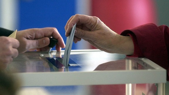 Wahlzettel wird in eine Wahlurne geworfen