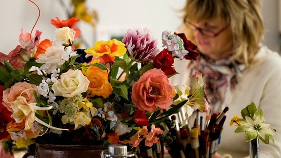 In einer Schauwerkstatt fertigt 2011 eine Mitarbeiterin in Handarbeit Kunstblumen an.