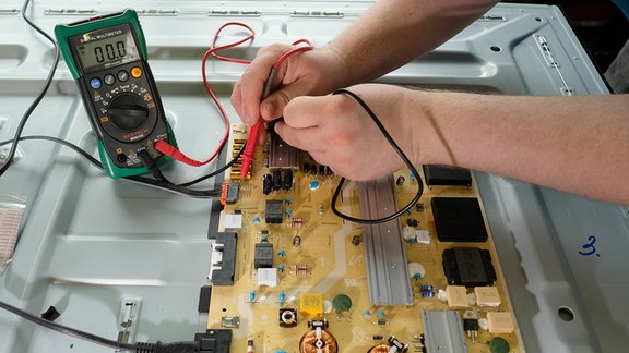 An einem Fernsehbildschirm werden in einer Reparaturwerkstatt elektronische Messgrößen ermittelt.