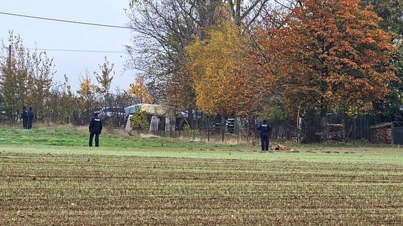 Beamte des Bundeskriminalamt (BKA) stehen während eines Einsatzes auf einem Feld.