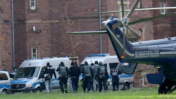 Vermummte Polizist*innen führen ein Gruppe Leute ab.