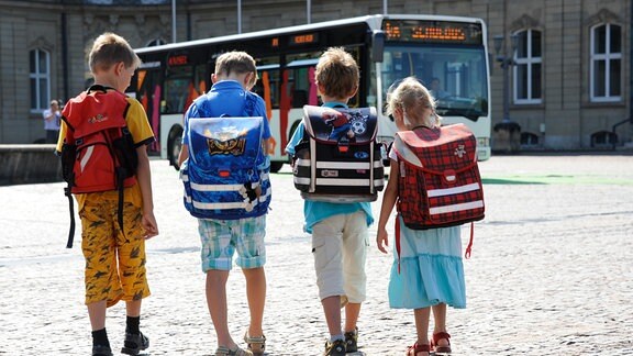 Kinder gehen auf einen Schulbus zu.