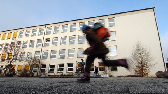 Ein Schüler läuft über einen Schulhof.