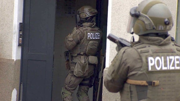 Beamte der Polizei stürmen ein Wohnhaus (Symbolbild)