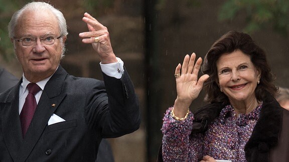 Königin Silvia von Schweden und König Carl XVI. Gustaf verabschieden sich winkend.