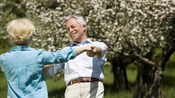 Zwei Senioren tanzen vor einem blühenden Baum