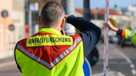 Ein Mitarbeiter der Verkehrsunfallforschung der Technischen Universität Dresden ist mit der Aufnahme von Messdaten nach einem Verkehrsunfall beschäftigt.