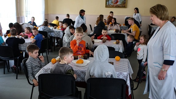 Kinder im Speisesaal eines Waisenhauses.