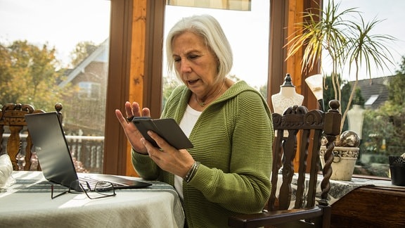 Seniorin mit Laptop und Smartphone