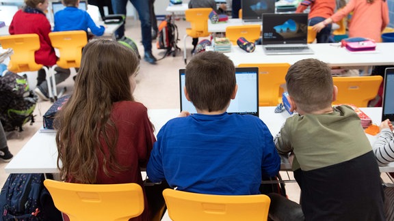 Schüler einer 3. Klasse sitzen während eines Presserundgangs in einem Klassenzimmer der Grundschule Georgius Agricola vor einem Laptop.
