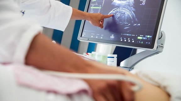 Ein Arzt einer Frauenklinik führt eine pränatale Ultraschall-Untersuchung an einer schwangeren Frau durch.