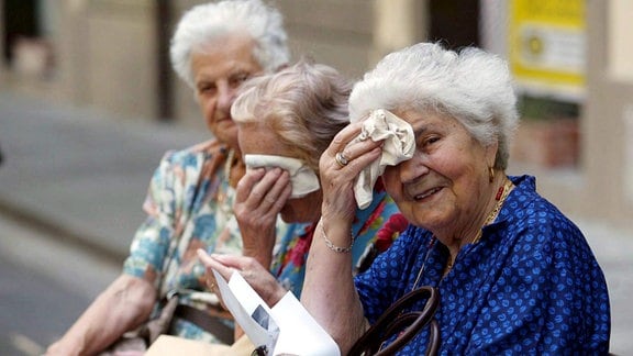 Ältere Frauen sitzen im Sommer auf einer Bank.