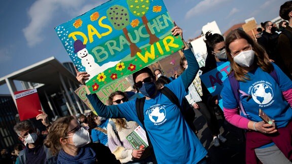 Demonstranten der Fridays For Future Bewegung mit Schild "Das Brauchen Wir".