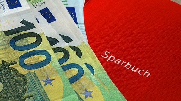 Ein rotes Sparbuch und Euro-Banknoten.